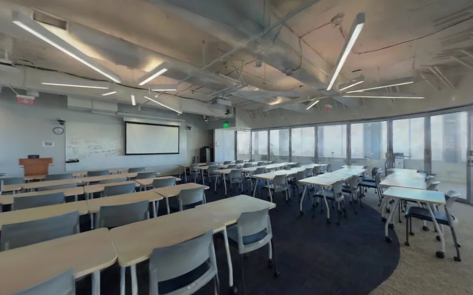 Rows of tables in a glass-walled classroom of the school floor twin, under star-shaped ceiling lights.